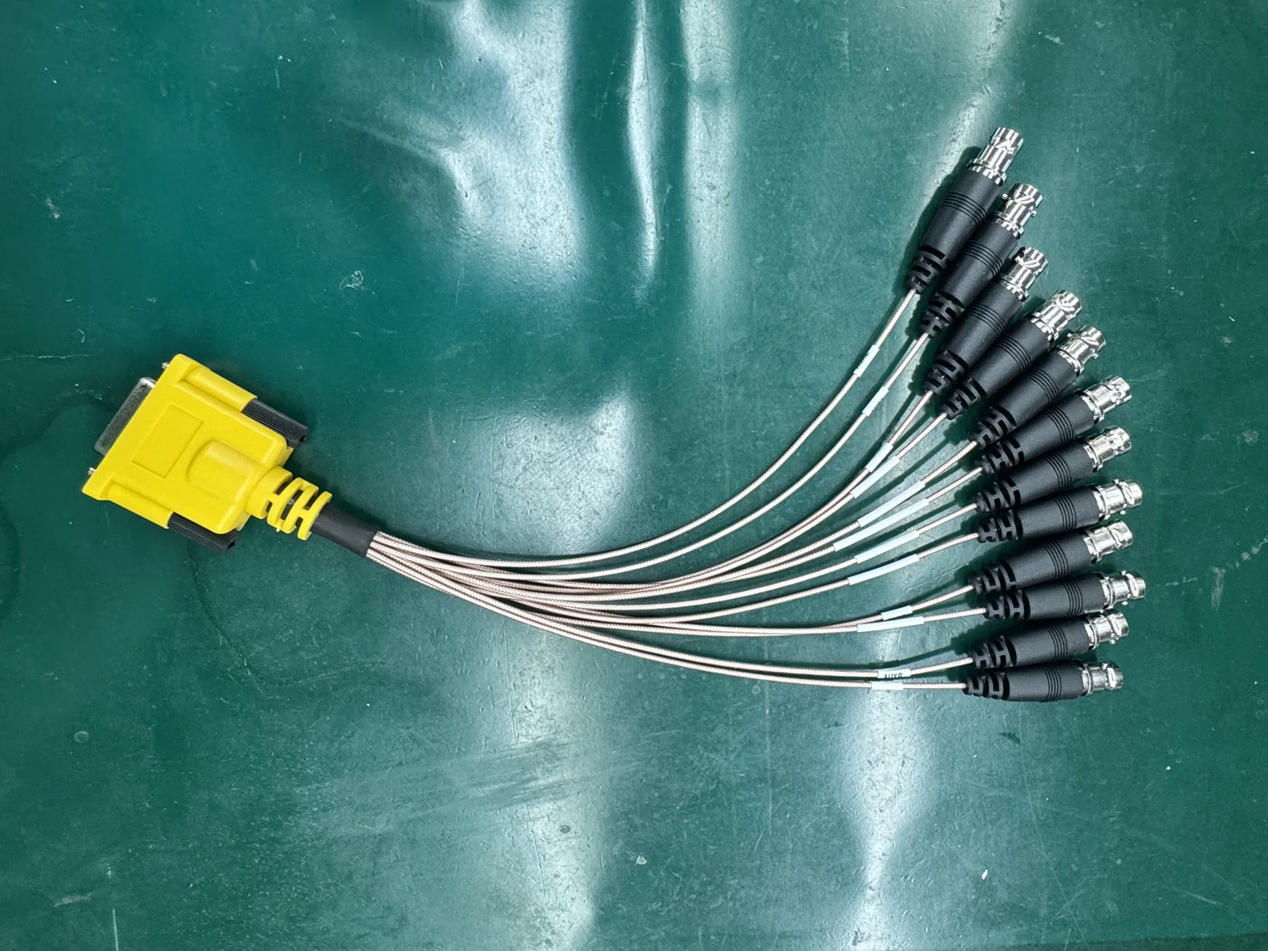 Yellow D-sub breakout cable assembly photographed on a green factory floor